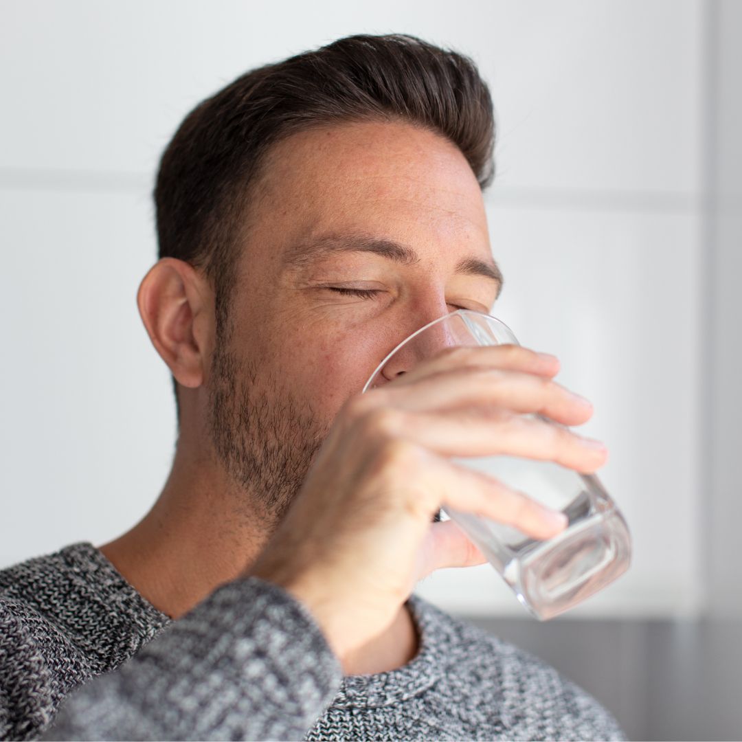 Man drinking water from a clear glass