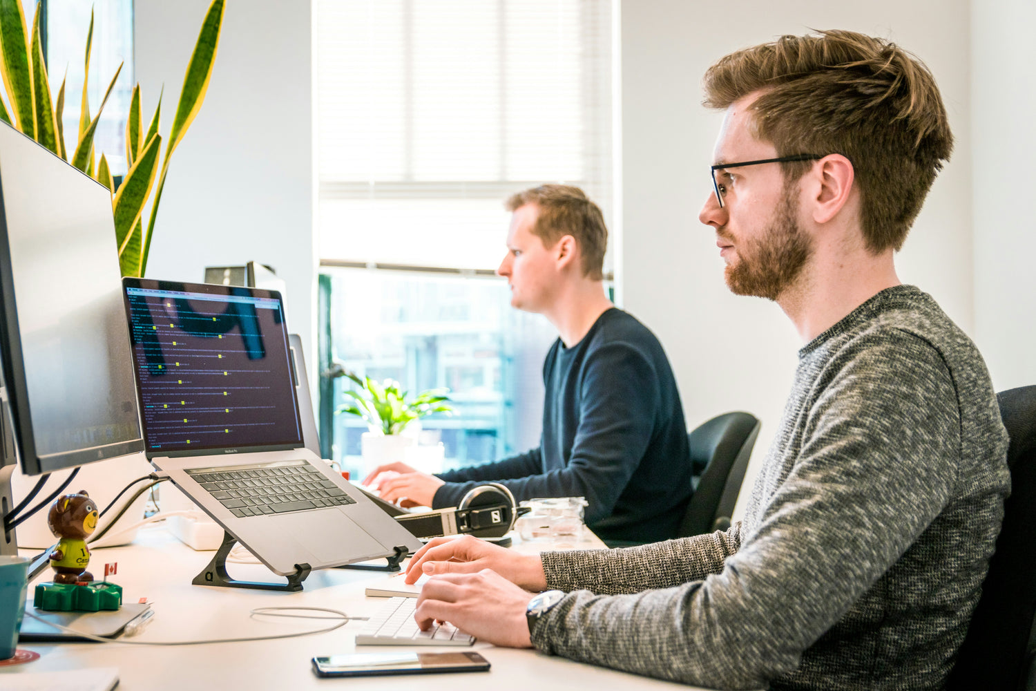 two men working on their computers in an office