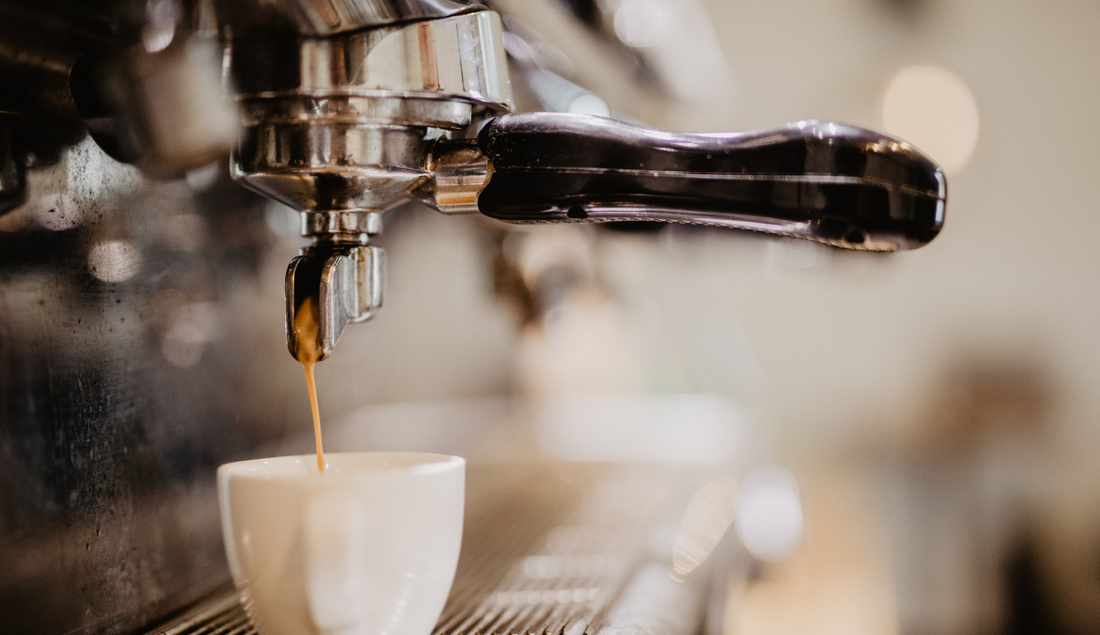 commercial coffee machine being used to brew a coffee and pour into a mug