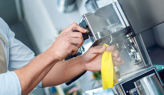 person using a rag to clean their commercial coffee machine